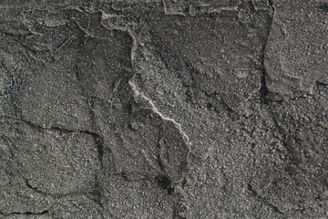Abstract background. Black textured wall in the street in the frost. Small snowflakes and frost on a dark shattered and flaky surface.