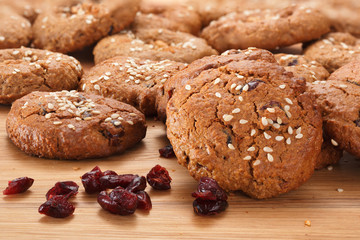 Homemade oatmeal cookies with  dried berries, nuts, chocolate chips and sesame. On a wooden background. Selective focus.