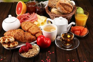 breakfast on table with bread buns, croissants, coffe and juice on valentines day.