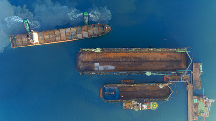 Aerial top view Tugboat drag container ship to shipyard for repair. Can use for shipping or transportation concept.
