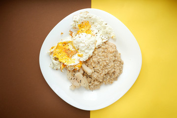 Nutritious breakfast of oatmeal and scrambled eggs on a bright background, top view