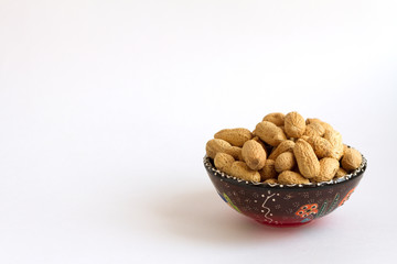 peanuts in shell on clay cup, monkey nuts on white background