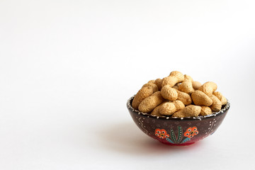 peanuts in shell on clay cup on white background. copy space