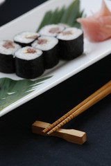 Rolls of sushi with rice nori seeweed and fish on a white plate with hashi chopsticks in a gourmet menu.