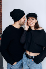 Two hipster models: a man and a woman in a blank black t-shirt, jeans and posing. in a black hat, cap, love, kisses