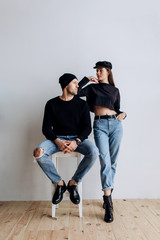 Two hipster models: a man and a woman in a blank black t-shirt, jeans and posing. in a black hat, cap, love, kisses