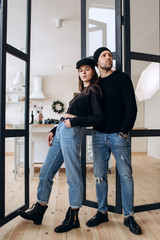 Two hipster models: a man and a woman in a blank black t-shirt, jeans and posing. in a black hat,...
