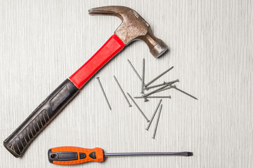 An image of hammer, screwdriver and nails on wooden table