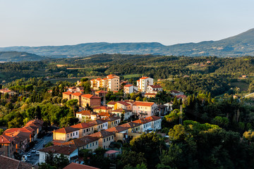 Chiusi village cityscape at sunrise in Umbria Italy street road cars and rooftop houses on mountain countryside and rolling hills