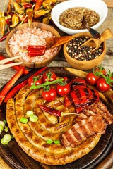 Grilled sausages spiral served on rustic round cutting board with mustard. Homemade barbecue. Garden party. Food preparation.