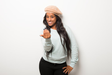 Young afro american woman on white wall presenting and inviting to come with hand