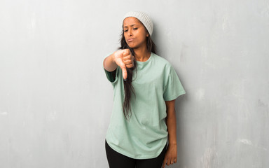 Young afro american woman on textured background showing thumb down sign with negative expression