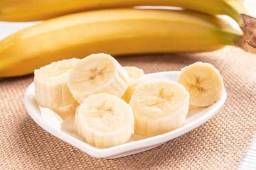 Sliced and whole bananas on a white plate and old wooden roofing