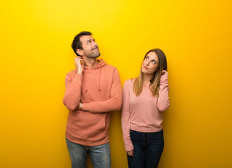 Group of two people on yellow background thinking an idea while scratching head