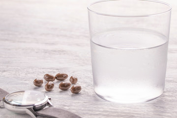 Misted glass of water and brown medical capsules on a white old wooden table. Wrist Watch