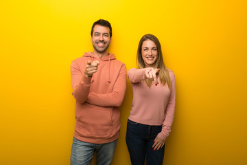 Fototapeta premium Group of two people on yellow background points finger at you with a confident expression