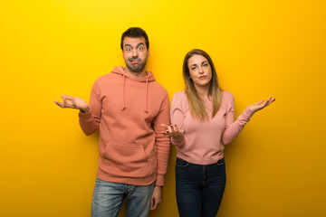 Fototapeta premium Group of two people on yellow background unhappy and frustrated with something because not understand something