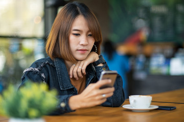 Young beautiful woman uses cellphone and listens to music in the coffee cafe