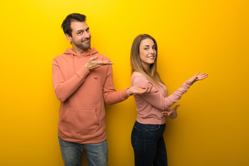Group of two people on yellow background extending hands to the side for inviting to come