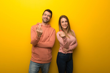 Group of two people on yellow background inviting to come with hand. Happy that you came