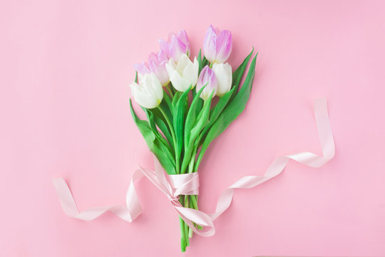 Bouquet of tulips on a pink pastel background. Wonderful spring breakfast on Mother's Day or Women. Flat lay. View top. Selective focus.