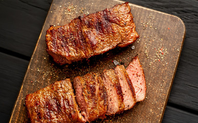 Beef steak on the cutting board with spices, wooden dark table