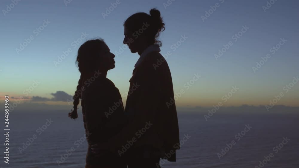 Wall mural Romantic couple embracing on hill top at dusk