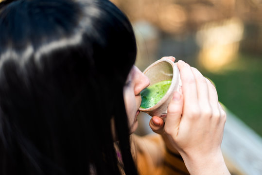 Woman Holding Tea Cup Face Closeup Drinking Outside In Backyard Garden With Girl And Green Matcha Black Hair