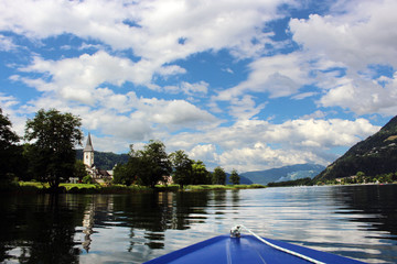 Beautiful view of the Ossiacher lake from the boat in the middle and blue cloudy sky as background