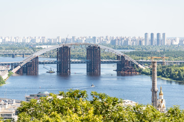 View of Kyiv town cityscape skyline with Soviet buildings in Kiev city residential suburbs neighborhood with Dnieper Dnepr river and old abandoned bridge in summer