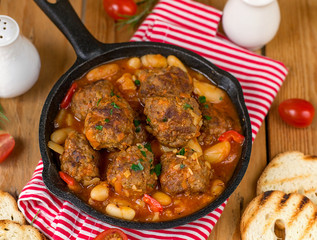 Meatballs from ground beef in tomato sauce with haricot beans
