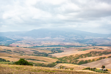 Val D'Orcia countryside in Tuscany, Italy with rolling plowed brown hills and villas with farm landscape idyllic picturesque meadow fields