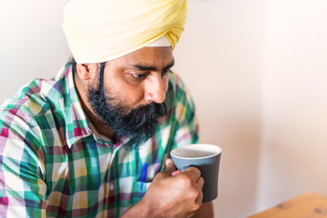 Indian with turban holding a cup of coffee