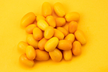 Ripe kumquats on yellow background

