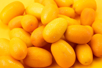 Ripe kumquats on yellow background
