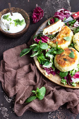 Cottage cheese pancakes or syrniki with cheese, green onion, dill and parsley served with salad mix and sour cream with mint.