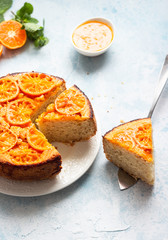 Upside down tangerine cake on a sky blue stone or concrete background.