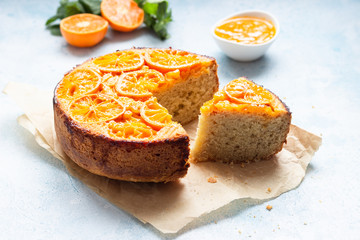 Upside down tangerine cake on a sky blue stone or concrete background.