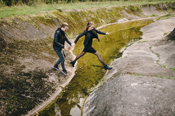 Obraz premium Young couple jumping over stream