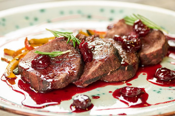 Grilled veal with smashed cherries, closeup. Veal with smashed cherries, rosemary and yellow pepper.