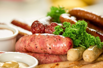Dish with different kinds of sausages. Different kinds of sausages with parsley and pot of mustard.