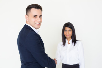 Smiling business colleagues greeting each other. Positive young man and woman in office clothes shaking hands. Handshake deal concept