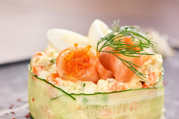 Salad with salmon wrapped with sliced cucumber. Round salad with salmon and cavair close up.