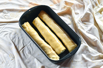 Rolled dough for strudel with curd cheese in it in a baking dish