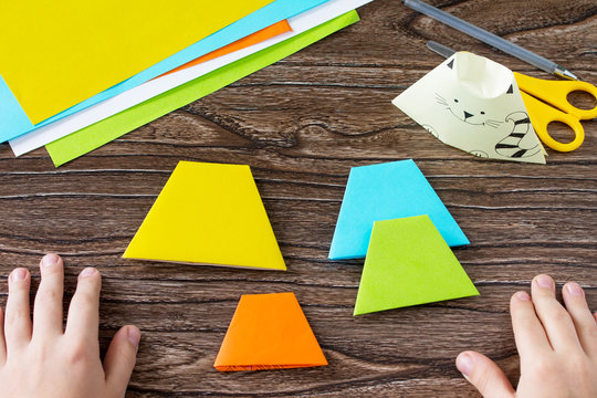 The child folds the parts various Origami toy made from paper puppets cat. Handmade. Project of children's creativity, handicrafts, crafts for kids.