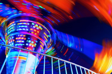 Abstract motion blur lighting and multicolored of carousel is spinning in amusement park, close up with low angle view