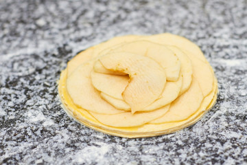 Many layers of apple slices on dough basis. Uncooked apple tart layers.