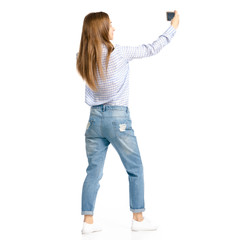 Obraz premium Woman in blue jeans and shirt smartphone selfie on white background isolation, back view