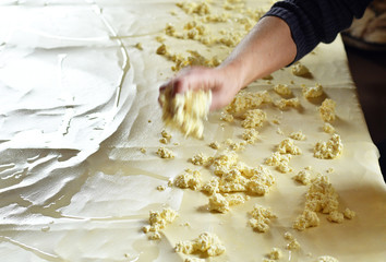Dough for strudel, stretched on a kitchen table and adding curd cheese on it