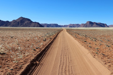 endless long road through the grass steppe with mountains - Namibia Africa